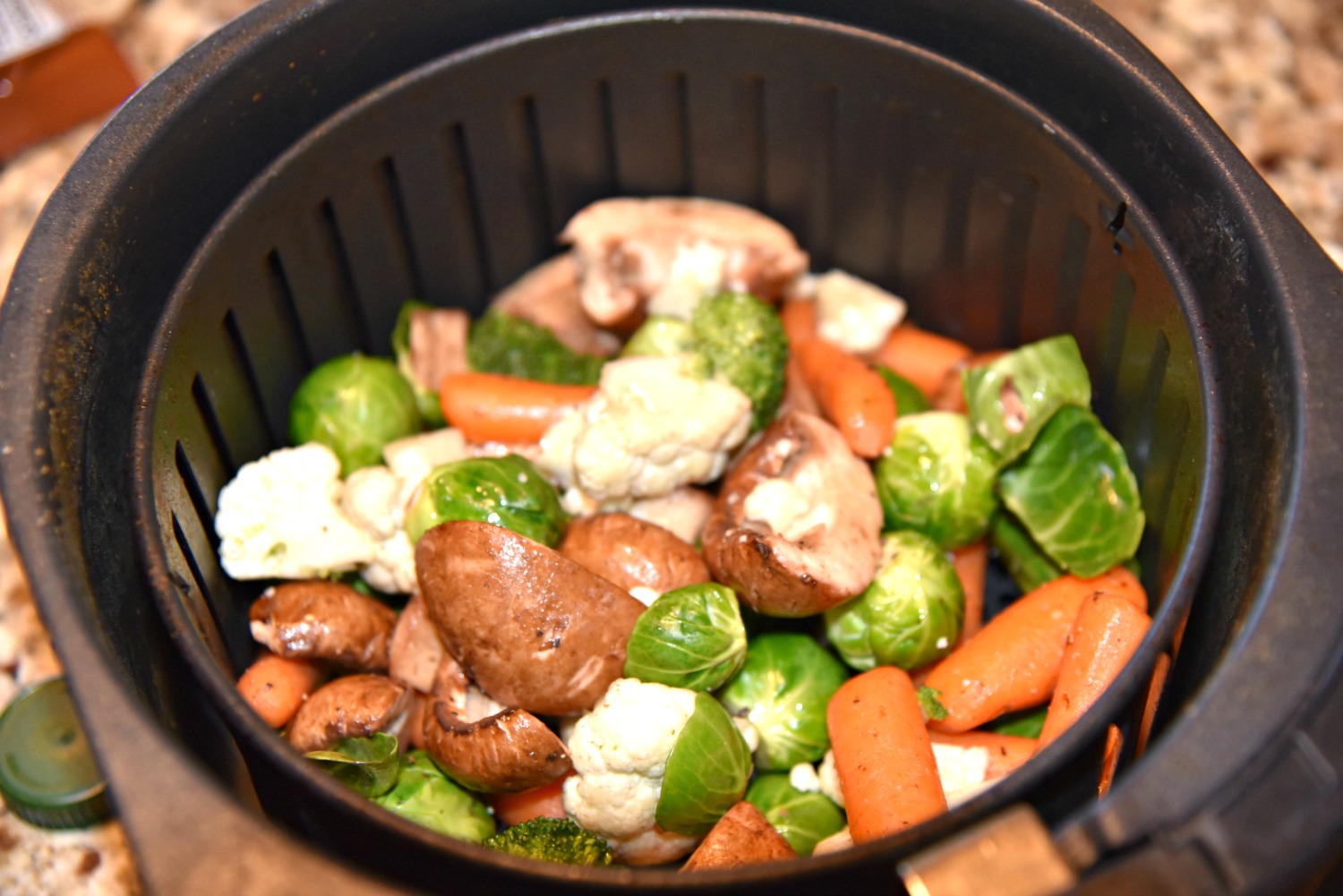 Vegetables tossed in olive oil and salt sitting in an Air Fryer Basket