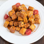Air Fryer Tofu made with a sweet and spicy sauce being served on a white plate.