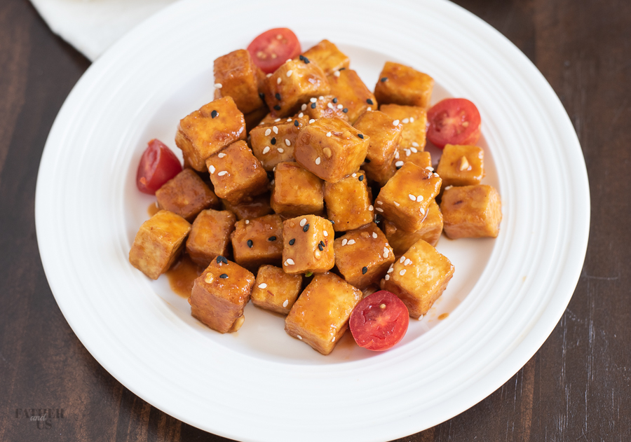 Air Fryer Tofu made with a sweet and spicy sauce being served on a white plate.