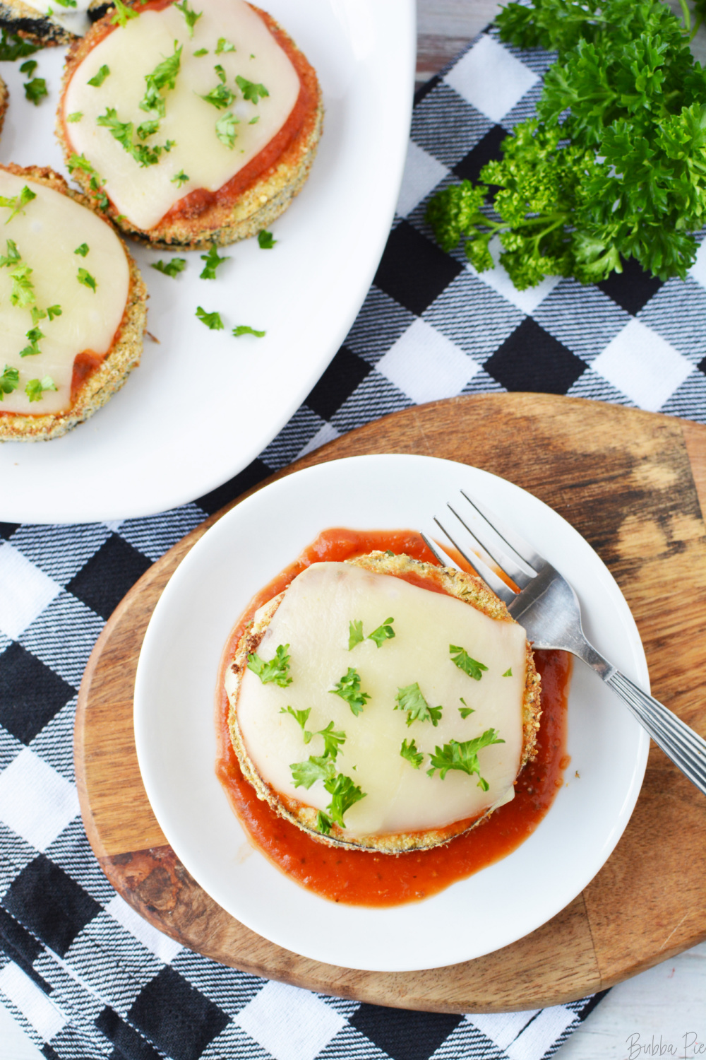 Eggplant Parmesan being served on a white plate with a fork.